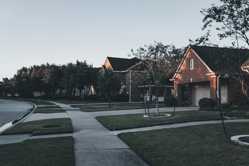 Serene suburban scene with brick houses and landscaped lawns at dusk.
