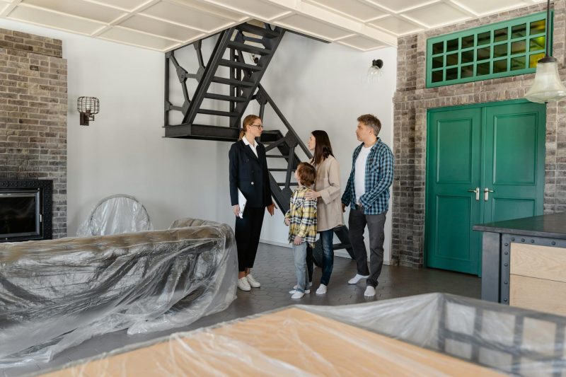 A family and a real estate agent tour a modern home, examining the sleek interiors.