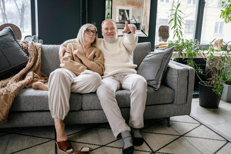 Happy senior couple relaxing together on a stylish sofa in a cozy, well-decorated living room.