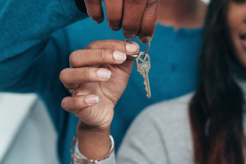 A couple joyfully holds a house key, symbolizing new home ownership or rental.