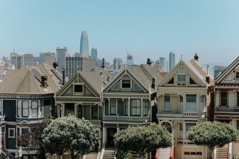 Colorful Victorian houses in San Francisco with a vibrant city skyline in the background.
