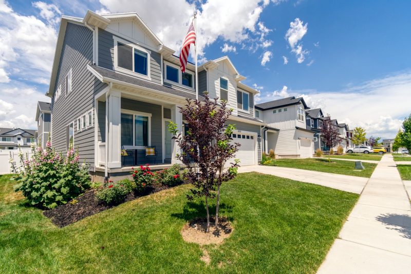 Modern suburban house with a garden and an American flag, featuring attractive architecture.