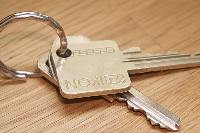 Set of metal house keys resting on a wooden surface.